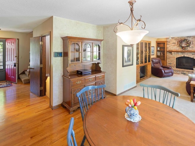 461 Dudley Ave, Shoreview, MN 55126 - dining room featuring light wood-style flooring, a brick fireplace, and a textured ceiling