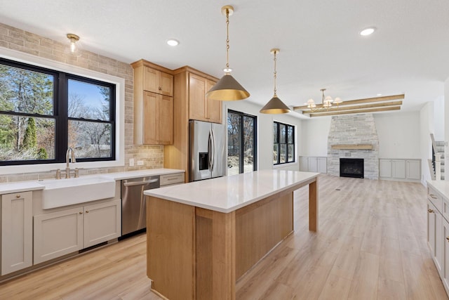 987 Island Lake Ave, Shoreview, MN 55126 - kitchen featuring stainless steel appliances, light wood finished floors, light countertops, a center island, and a stone fireplace