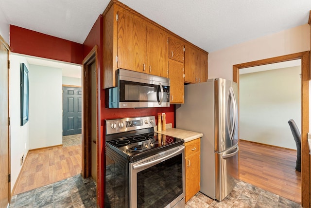 1111 Edgewater Ave, Arden Hills, MN 55112 - kitchen with appliances with stainless steel finishes, brown cabinetry, light countertops, and light wood-type flooring
