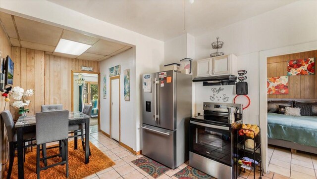114 Fairview Ave NW, Long Prairie, MN 56347 - kitchen featuring appliances with stainless steel finishes, under cabinet range hood, light tile patterned flooring, and wooden walls