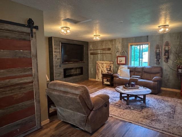 1415 Riverside Dr NW Unit 1415, Baudette, MN 56623 - living room featuring wood finished floors, a textured ceiling, a fireplace, and a barn door