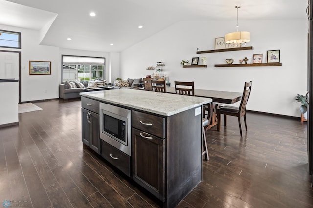 6028 59th Ave S, Fargo, ND 58104 - kitchen with stainless steel microwave, a breakfast bar, dark brown cabinets, dark wood finished floors, and vaulted ceiling