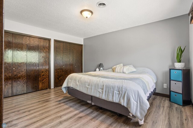 21 35th Ave NE, Fargo, ND 58102 - bedroom featuring wood finished floors, multiple closets, and a textured ceiling