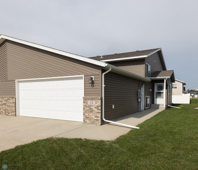 34 Cedar Dr, Mapleton, ND 58059 - view of home's exterior featuring concrete driveway, a lawn, brick siding, an attached garage, and roof with shingles