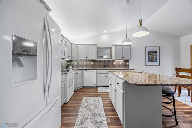 3437 26th Ave S, Fargo, ND 58103 - kitchen with white appliances, vaulted ceiling, a kitchen island, tasteful backsplash, and a kitchen breakfast bar