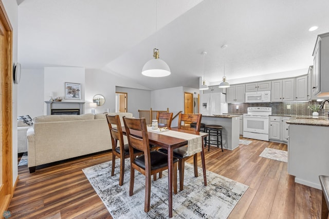 3437 26th Ave S, Fargo, ND 58103 - dining room featuring light wood finished floors, vaulted ceiling, and a fireplace