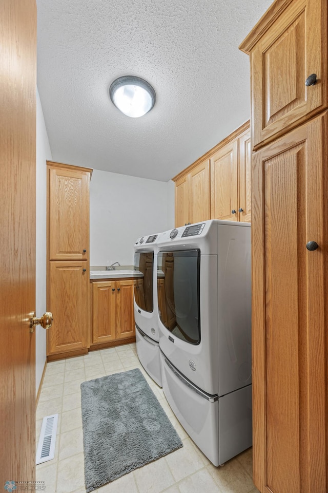 3437 26th Ave S, Fargo, ND 58103 - washroom with separate washer and dryer, cabinet space, light tile patterned floors, and a textured ceiling