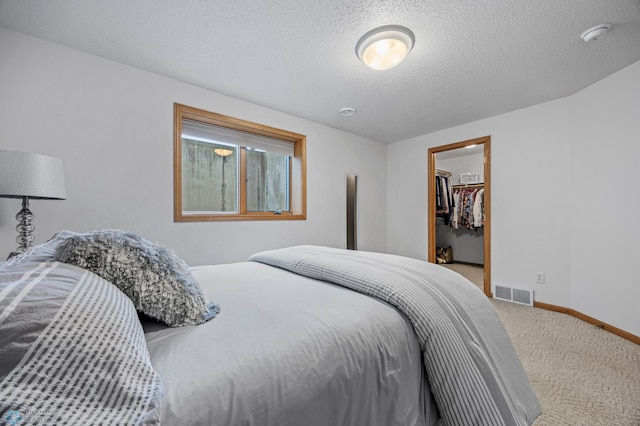 3437 26th Ave S, Fargo, ND 58103 - bedroom with carpet floors, a textured ceiling, and a walk in closet