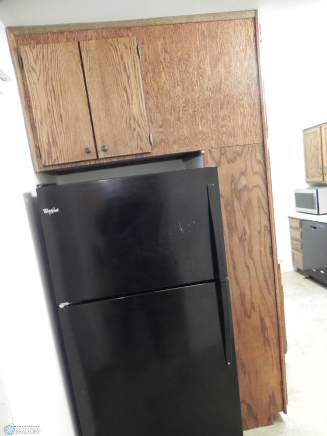1610 9th St N, Fargo, ND 58102 - kitchen view of freestanding refrigerator, white microwave, light carpet, and brown cabinets