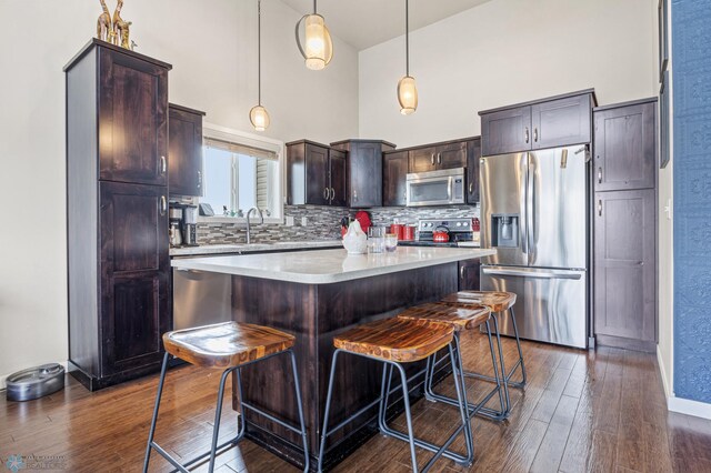708 30th Ter E, West Fargo, ND 58078 - kitchen featuring stainless steel appliances, a towering ceiling, dark wood-style flooring, dark brown cabinetry, and a breakfast bar area