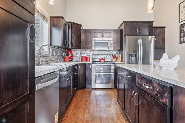 708 30th Ter E, West Fargo, ND 58078 - kitchen featuring stainless steel appliances, tasteful backsplash, dark brown cabinetry, light stone countertops, and wood finished floors