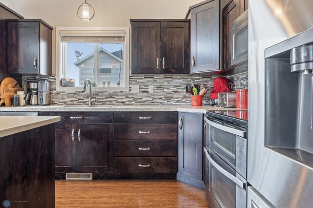 708 30th Ter E, West Fargo, ND 58078 - kitchen with appliances with stainless steel finishes, backsplash, dark brown cabinetry, and light wood-type flooring