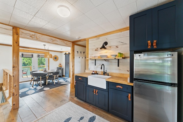 13491 80th St NW, Annandale, MN 55302 - kitchen featuring freestanding refrigerator, wood counters, blue cabinets, open shelves, and light wood-style flooring