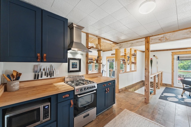 13491 80th St NW, Annandale, MN 55302 - kitchen with blue cabinets, appliances with stainless steel finishes, wall chimney exhaust hood, wooden counters, and wood finished floors