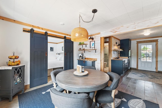 13491 80th St NW, Annandale, MN 55302 - dining space with hardwood / wood-style flooring, a barn door, and wooden walls