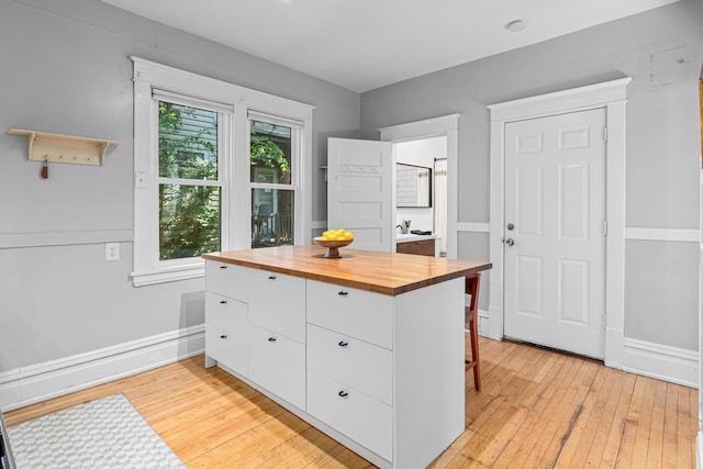 1066 Woodbridge St, Saint Paul, MN 55117 - kitchen featuring butcher block countertops, white cabinetry, light wood-style floors, and a kitchen breakfast bar