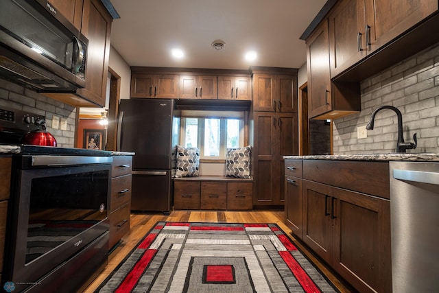 1606 5th St N, Fargo, ND 58102 - kitchen with stainless steel appliances, light wood finished floors, decorative backsplash, and light stone countertops