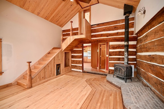 S3093 Baertsch Valley Rd, Cross Twp, WI 54629 - unfurnished living room featuring a wood stove, wood walls, high vaulted ceiling, wood-type flooring, and stairway