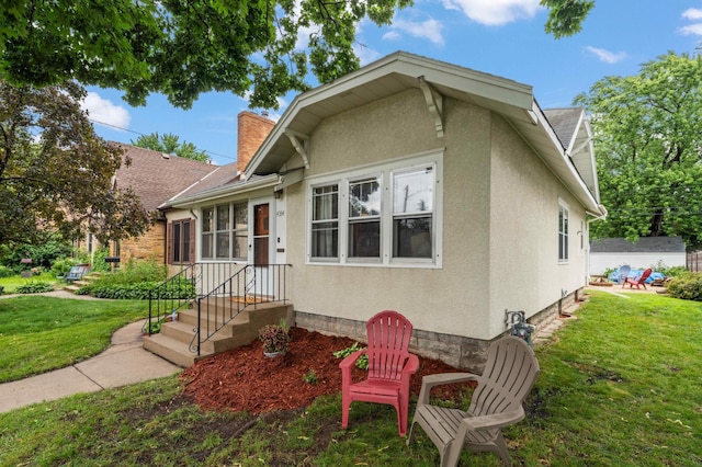 4334 Thomas Ave N, Minneapolis, MN 55412 - bungalow-style house featuring a front lawn, a chimney, and stucco siding