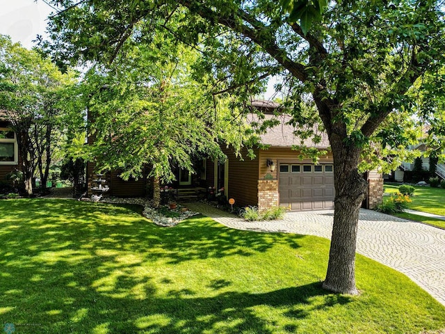 15 Fremont Dr S, Fargo, ND 58103 - view of property hidden behind natural elements featuring driveway, a front yard, brick siding, and a garage