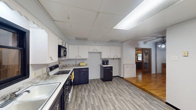 500 Main Ave, Lafayette, MN 56054 - kitchen with black microwave, light wood finished floors, white cabinetry, electric stove, and light countertops