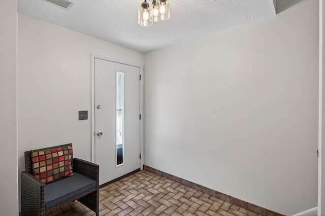2365 Dorland Ln E, Maplewood, MN 55119 - entryway with a textured ceiling, brick patterned flooring, and a chandelier
