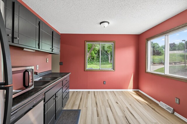 2365 Dorland Ln E, Maplewood, MN 55119 - kitchen featuring stainless steel appliances, light wood-style floors, dark countertops, and a textured ceiling