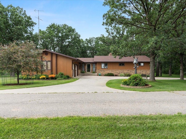 15170 141st Ave, Wadena, MN 56482 - view of front facade featuring curved driveway, a front yard, a chimney, stone siding, and a garage