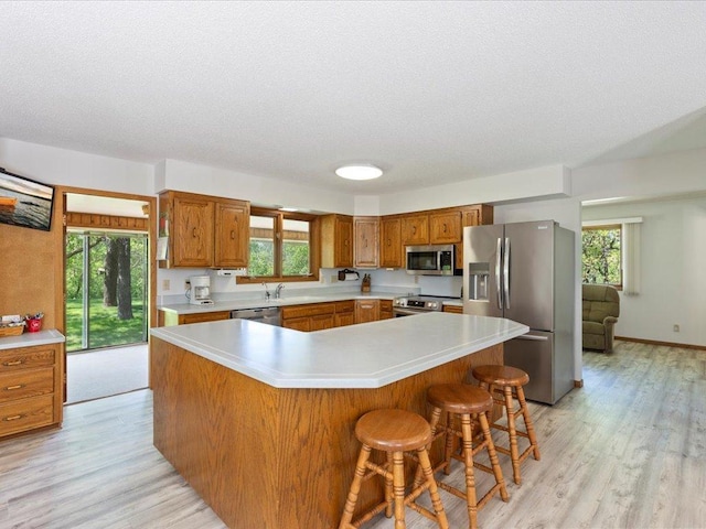 15170 141st Ave, Wadena, MN 56482 - kitchen with stainless steel appliances, brown cabinetry, light wood finished floors, and a textured ceiling