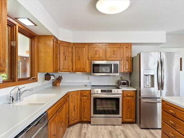 15170 141st Ave, Wadena, MN 56482 - kitchen featuring stainless steel appliances, brown cabinetry, light wood-type flooring, light countertops, and a textured ceiling