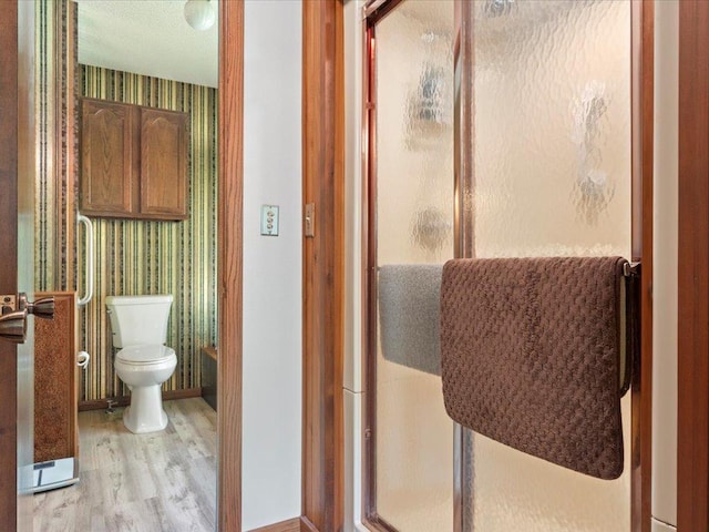 15170 141st Ave, Wadena, MN 56482 - full bathroom featuring wallpapered walls, wood finished floors, and a stall shower