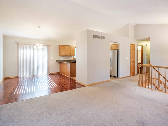 1618 Teton Ct NE, Rochester, MN 55906 - unfurnished living room with a chandelier, carpet flooring, vaulted ceiling, and wood finished floors
