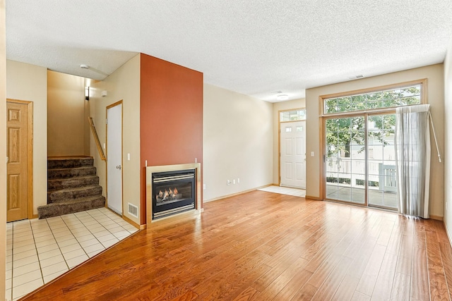 3730 Vermilion Ct S Unit 509, Eagan, MN 55122 - unfurnished living room with light wood-style floors, stairway, a textured ceiling, and a glass covered fireplace