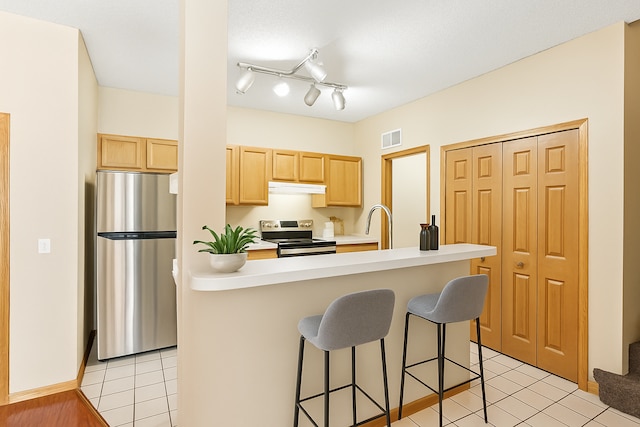 3730 Vermilion Ct S Unit 509, Eagan, MN 55122 - kitchen with appliances with stainless steel finishes, light brown cabinets, under cabinet range hood, a breakfast bar, and light tile patterned flooring