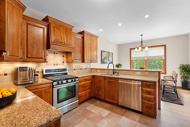 2309 Teakwood Ln SW, Rochester, MN 55902 - kitchen with stainless steel appliances, a peninsula, brown cabinets, light stone counters, and recessed lighting