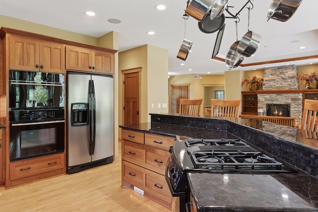 9449 Ehler Ave SE, Delano, MN 55328 - kitchen with stainless steel refrigerator with ice dispenser, gas range, a fireplace, light wood-style flooring, and dark stone counters