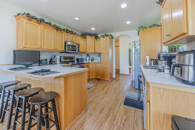 17123 Lakeview Ln, Audubon, MN 56511 - kitchen featuring arched walkways, stainless steel appliances, a peninsula, light wood-style flooring, and a breakfast bar area
