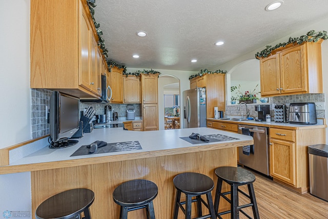 17123 Lakeview Ln, Audubon, MN 56511 - kitchen with appliances with stainless steel finishes, arched walkways, a peninsula, light countertops, and light wood-style flooring