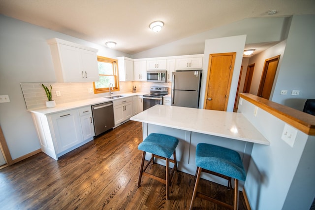 724 50th Ave NW, Rochester, MN 55901 - kitchen with appliances with stainless steel finishes, a kitchen bar, lofted ceiling, decorative backsplash, and dark wood finished floors