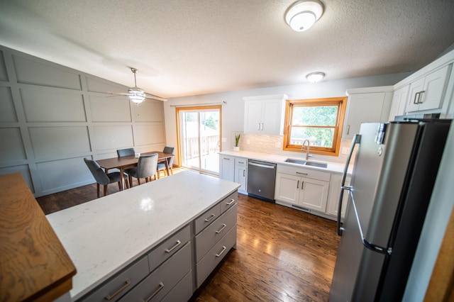724 50th Ave NW, Rochester, MN 55901 - kitchen featuring appliances with stainless steel finishes, white cabinetry, dark wood-type flooring, backsplash, and a ceiling fan
