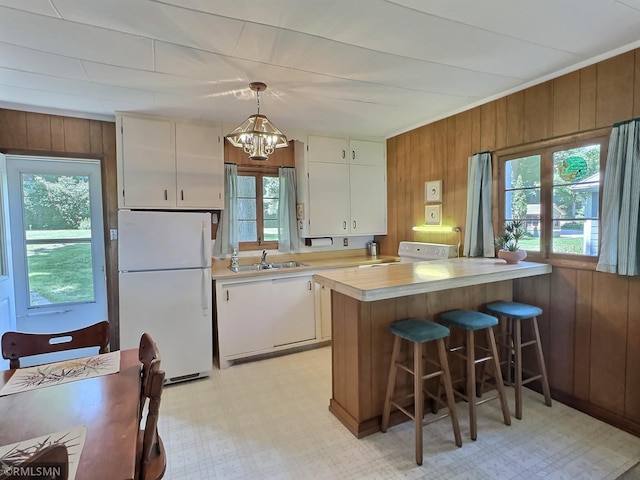 11436 Hoyer Ave NW, Annandale, MN 55302 - kitchen featuring white appliances, light countertops, wooden walls, a chandelier, and plenty of natural light