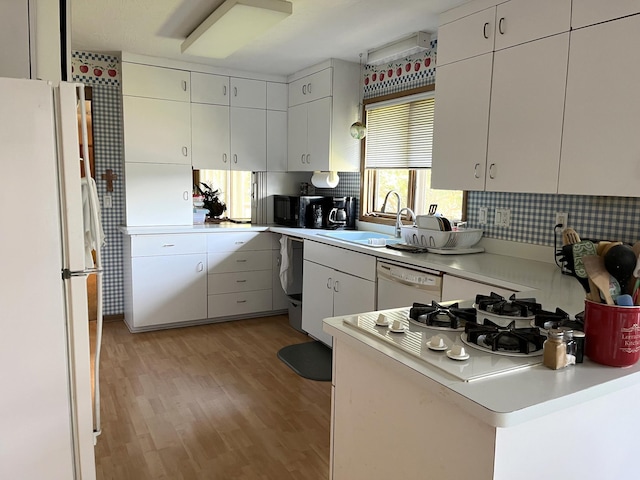 806 Highland Rd, Windom, MN 56101 - kitchen featuring white appliances, light wood-style floors, light countertops, a peninsula, and white cabinetry