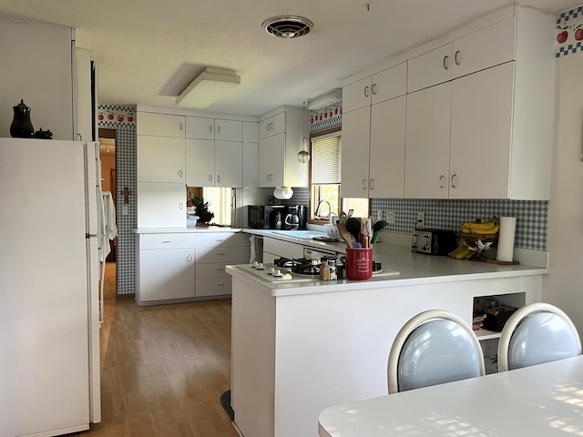 806 Highland Rd, Windom, MN 56101 - kitchen featuring freestanding refrigerator, a peninsula, light wood-type flooring, tasteful backsplash, and light countertops