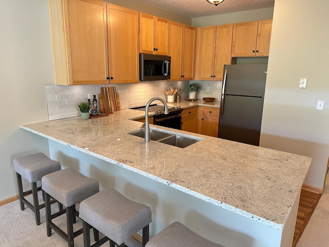 2100 Old School Rd Unit 206, Mound, MN 55364 - kitchen featuring appliances with stainless steel finishes, a peninsula, light stone counters, backsplash, and a kitchen bar