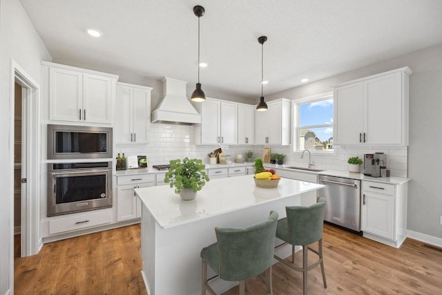 898 Laurel Ct, Chaska, MN 55318 - kitchen with stainless steel appliances, custom range hood, white cabinets, tasteful backsplash, and recessed lighting