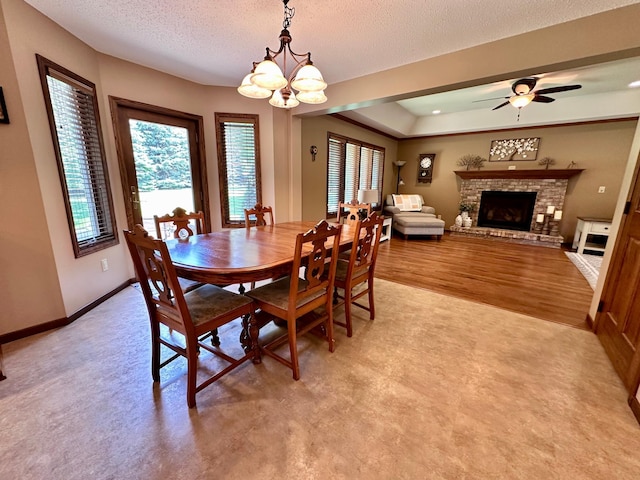 1201 Morningside Cir, Marshall, MN 56258 - dining space featuring a fireplace with raised hearth, healthy amount of natural light, a chandelier, a textured ceiling, and a ceiling fan