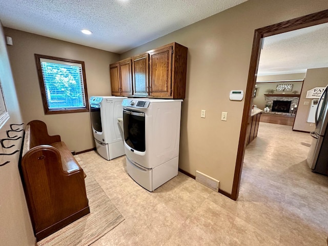 1201 Morningside Cir, Marshall, MN 56258 - laundry area with light flooring, a textured ceiling, washing machine and dryer, a fireplace with raised hearth, and cabinet space