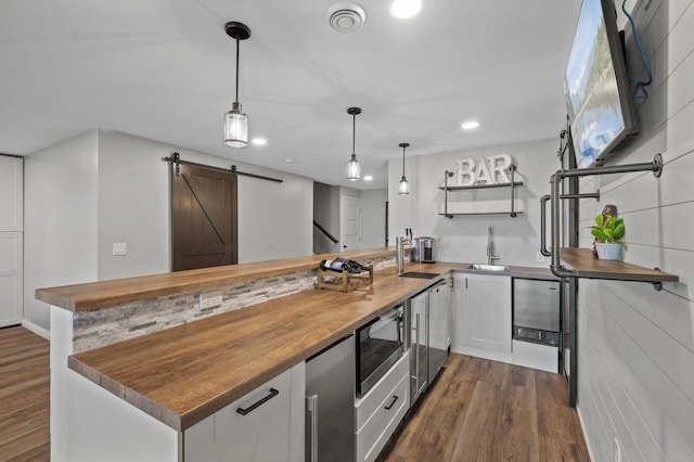 7850 242nd St, Wyoming, MN 55025 - kitchen featuring butcher block countertops, stainless steel microwave, dark wood-type flooring, a barn door, and white cabinets