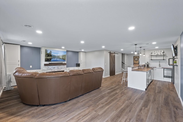 7850 242nd St, Wyoming, MN 55025 - living room with a barn door, recessed lighting, dark wood-style flooring, and bar with sink