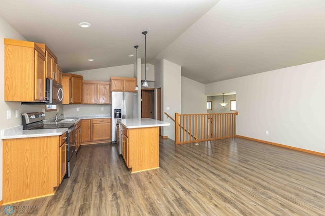 2054 12th St W, West Fargo, ND 58078 - kitchen with appliances with stainless steel finishes, vaulted ceiling, a kitchen island, light countertops, and dark wood-type flooring